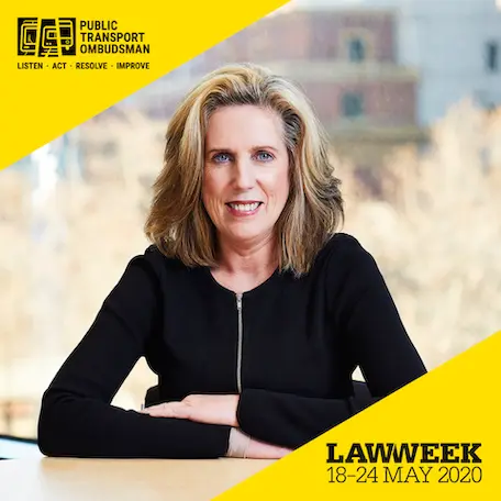 A woman with shoulder-length blonde hair, wearing a black jacket, smiles while seated at a desk. The image includes a yellow banner at the bottom with the text
